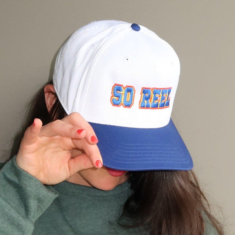 Load image into Gallery viewer, Person wearing a white and blue cap with 'SO REEL' text on a plain background